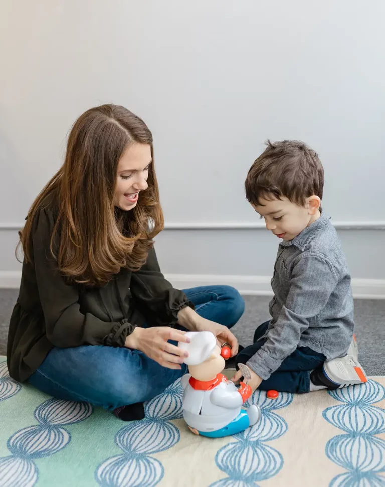 A speech therapist plays with a child. This links to a blog post about the importance in play as language learning practice.